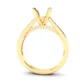 Yellow gold engagement ring setting with a four-prong mount for a central gemstone. Beneath the mount, a curved bridge features a row of small round diamonds. The polished band has a sleek, modern profile.